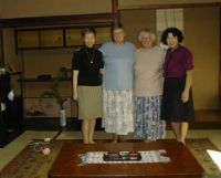 Kumi Pat Sandy and Hidelo in her living room.